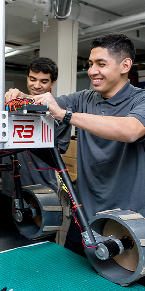 enginering students looking at a robot