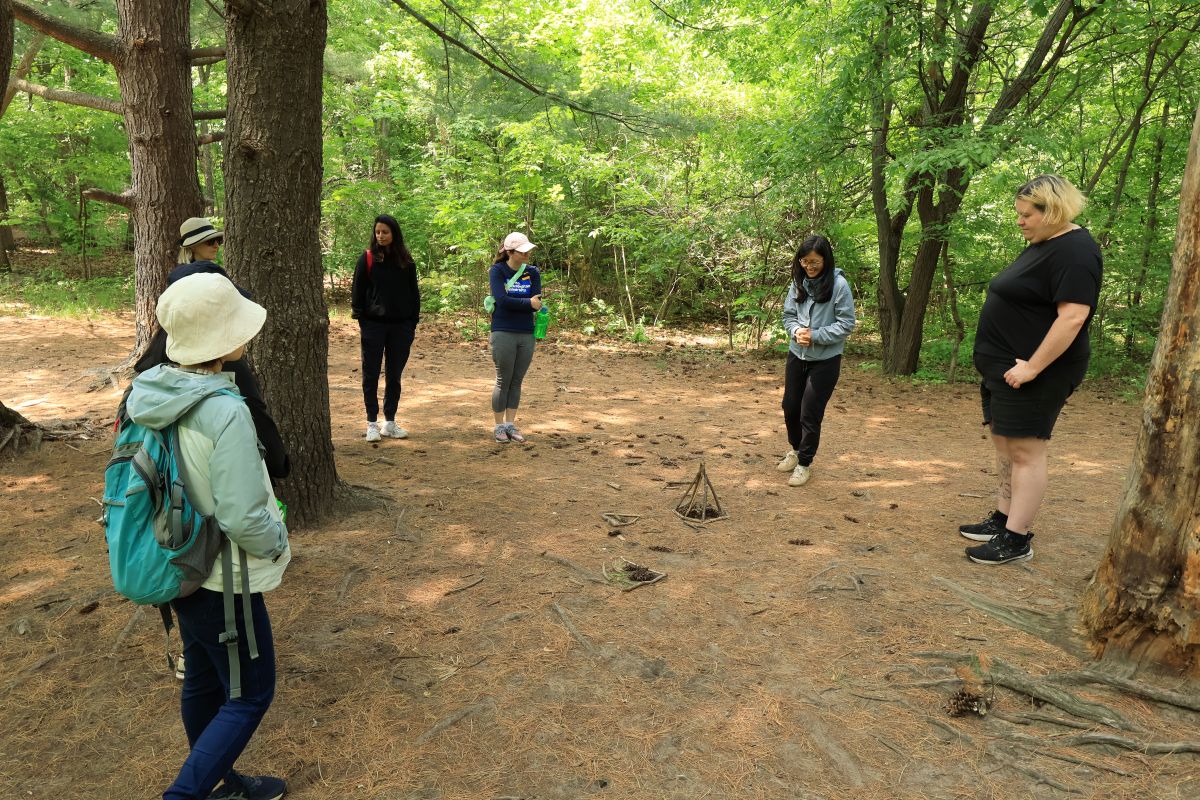 A group of forest bathing participants looking at their monuments, which were made with forest materials, and sharing stories.