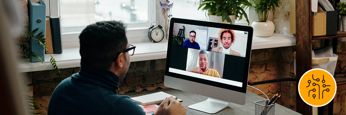 A man on his computer at home conducting a virtual meeting with three people.