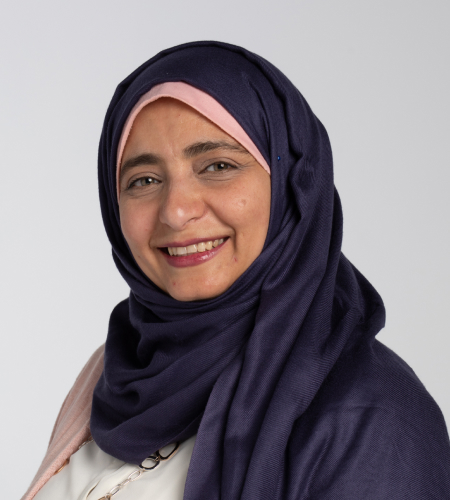 Headshot of Reem El Asaleh. She is smiling while wearing a dark blue hijab, white shirt, and pink cardigan.