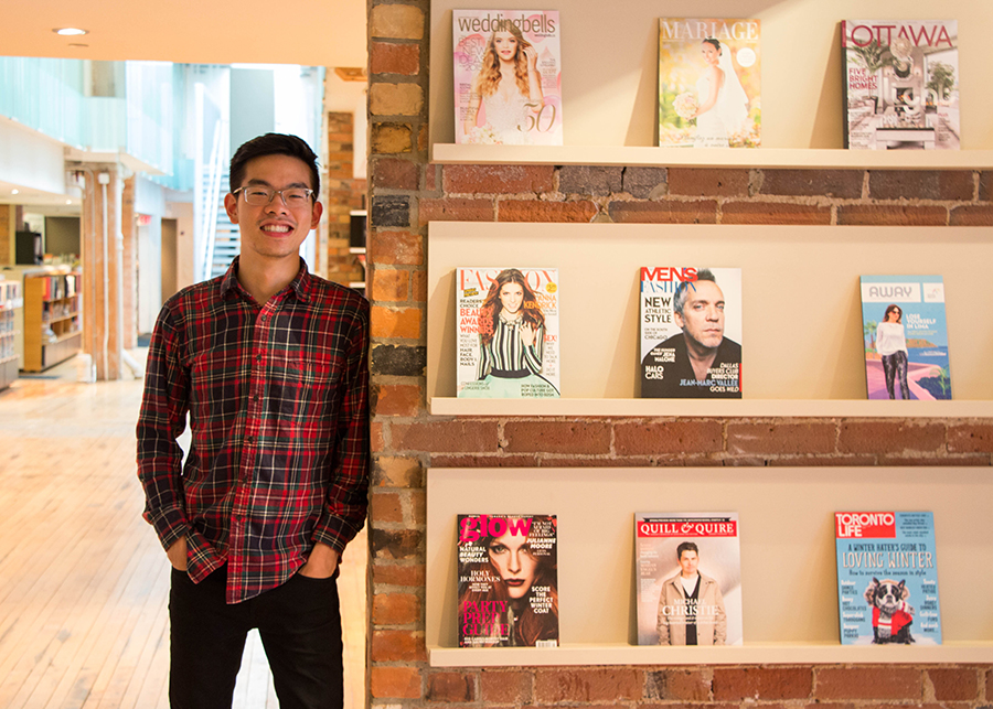 An intern posing in front of a wall of magazines.
