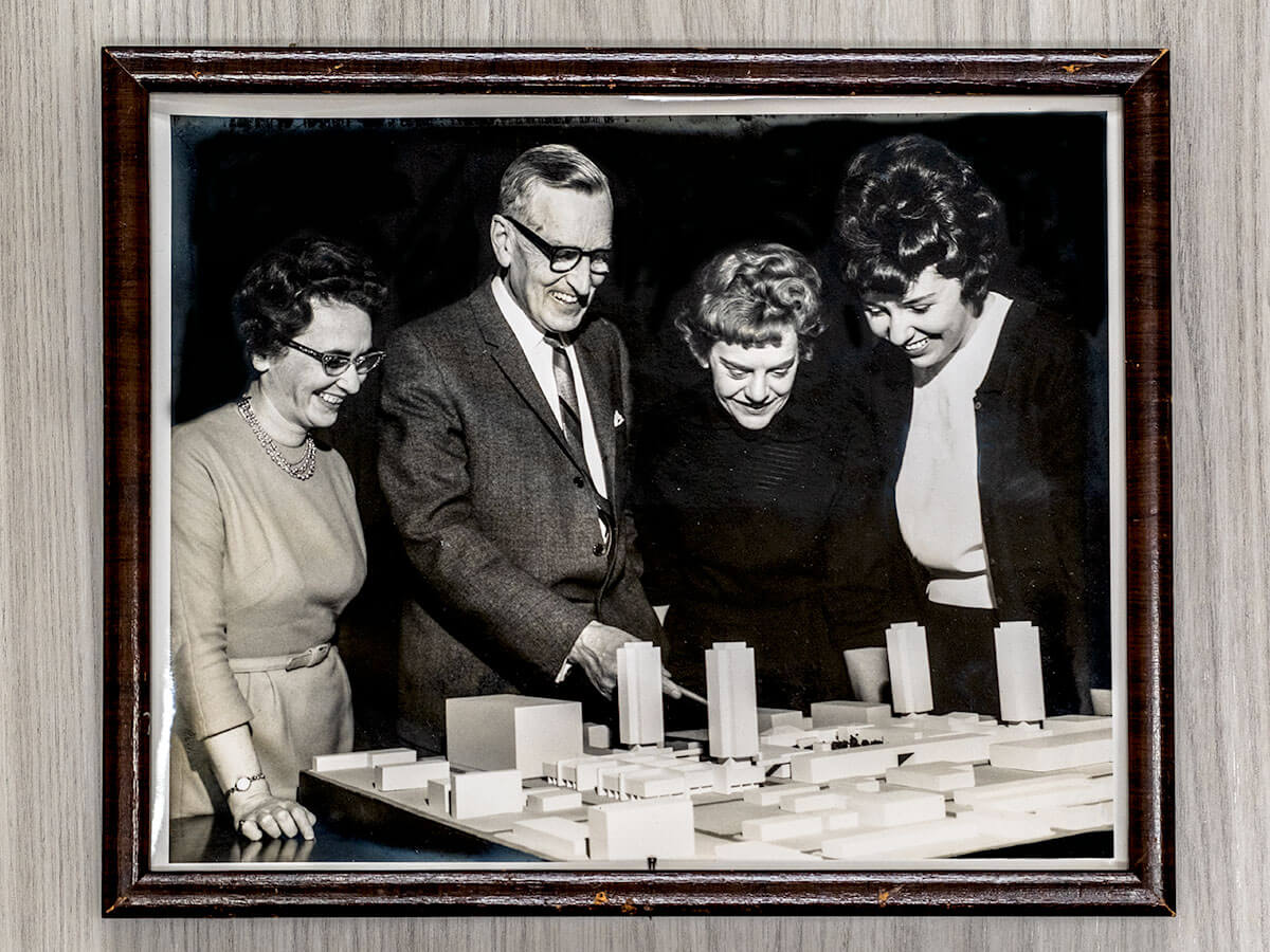 Audrrey Bowes, pictured with other TMU colleagues looking and smiling at a model other the TMU campus buildings.