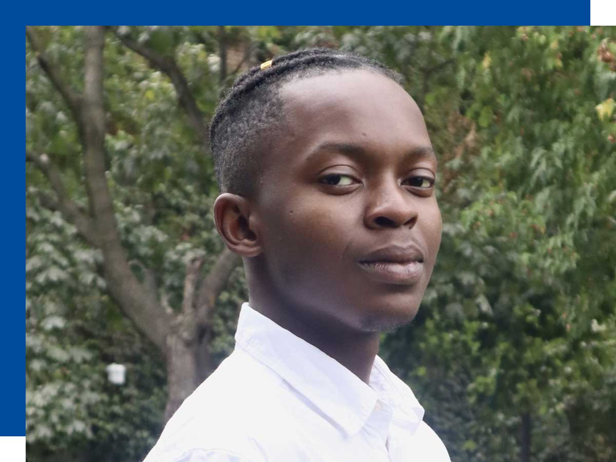 TMU student Adrian Omoruyi is looking at the camera with a slightly grin, against a background of green trees.