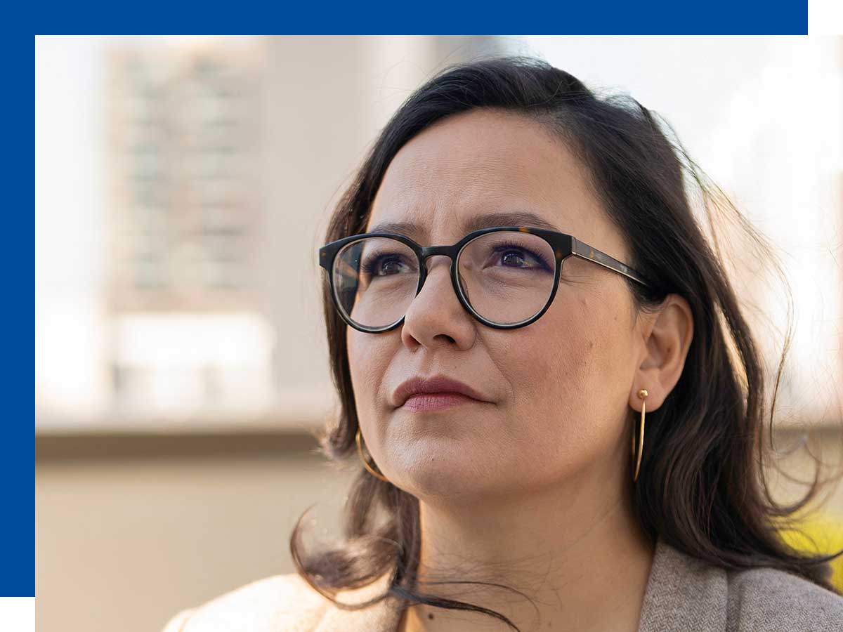  A headshot of Connie Walker, a Cree journalist and professor at Toronto Metropolitan University. She has long dark hair and is wearing a dark top, looking directly at the camera with a serious and professional expression.