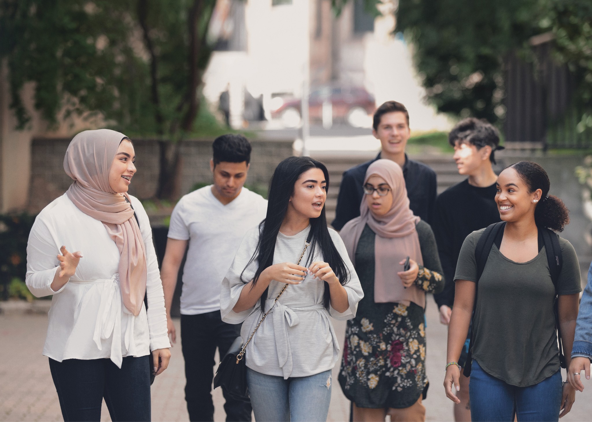 A diverse group of students walking together outdoors, engaged in conversation and smiling.