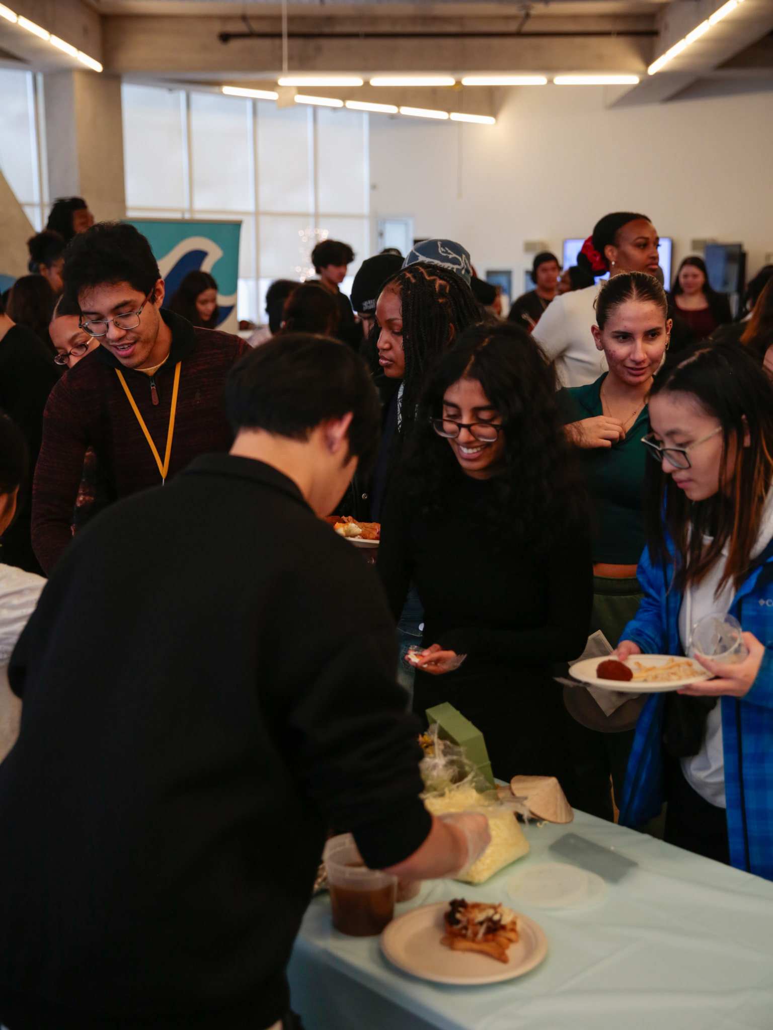 Students gathered at a food table during a campus event, being served various dishes.