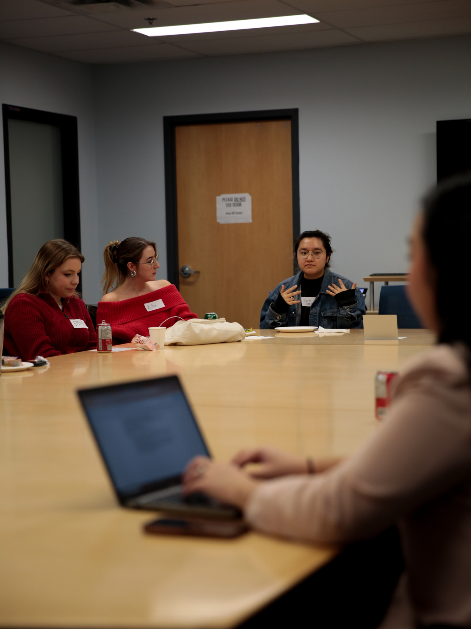 Students seated around a conference table engaged in discussion during a meeting or workshop.