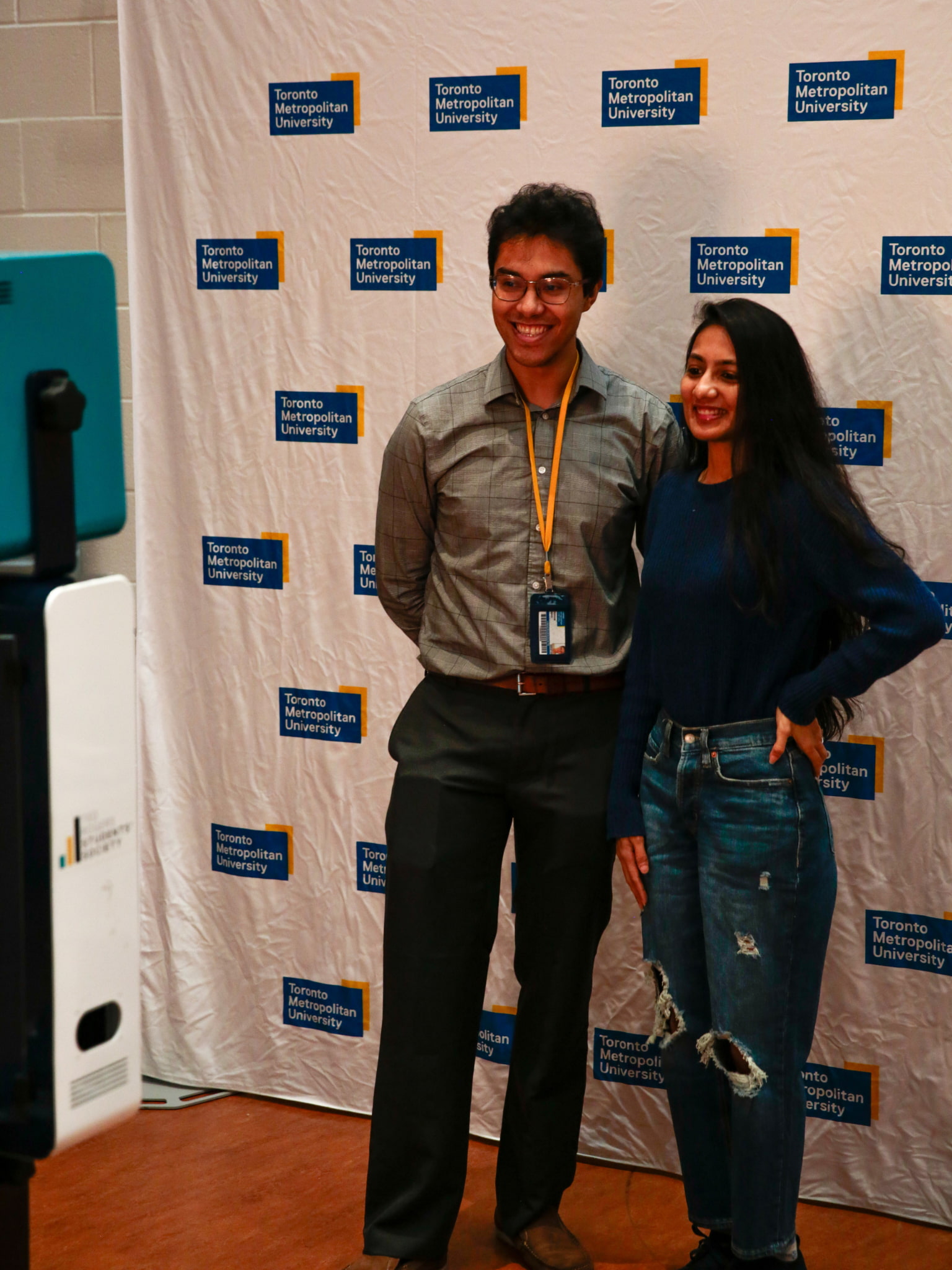 Two people smiling for a photo in front of a Toronto Metropolitan University step-and-repeat backdrop.