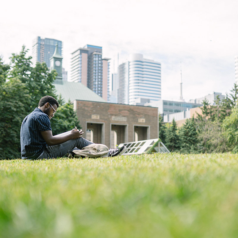 Ryerson student reading on the grass in the Quad on a sunny day.