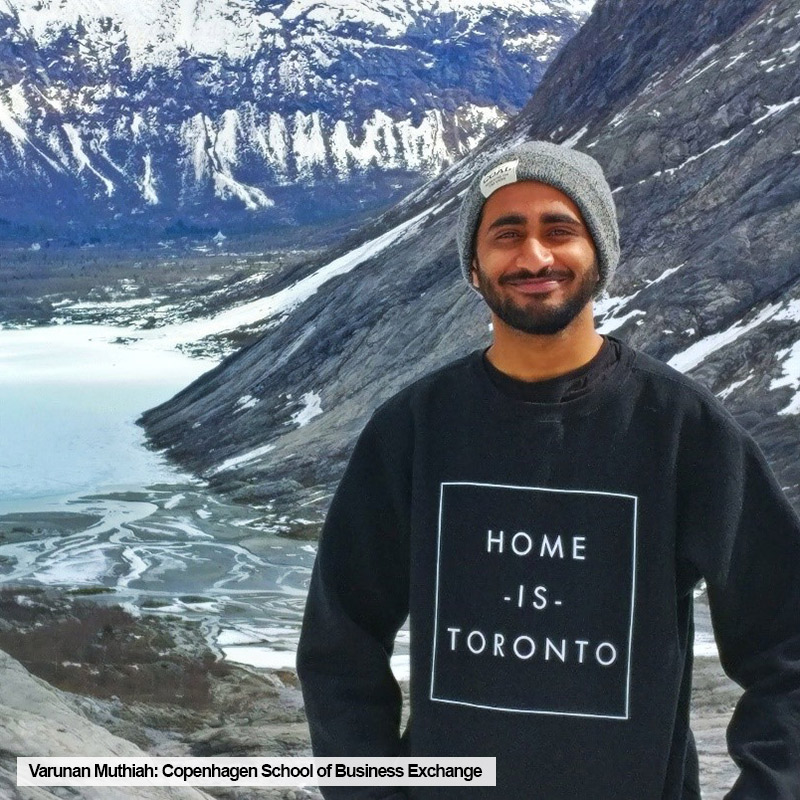 Ryerson TRSM student, Varunan Muthiah, wearing "Toronto is Home" sweater, poses with mountain range during a trip to Norway while on exchange at Copenhagen School of Business.