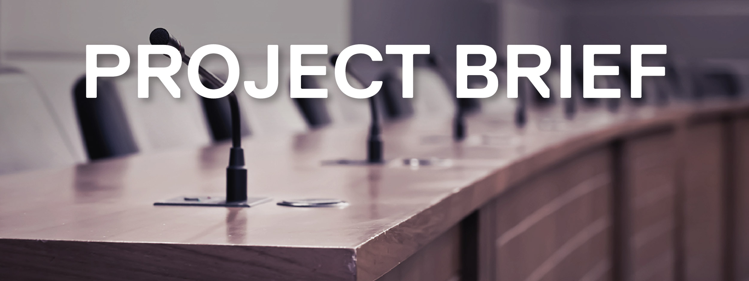 Microphones on top of a long desk with chairs surrounding the desks