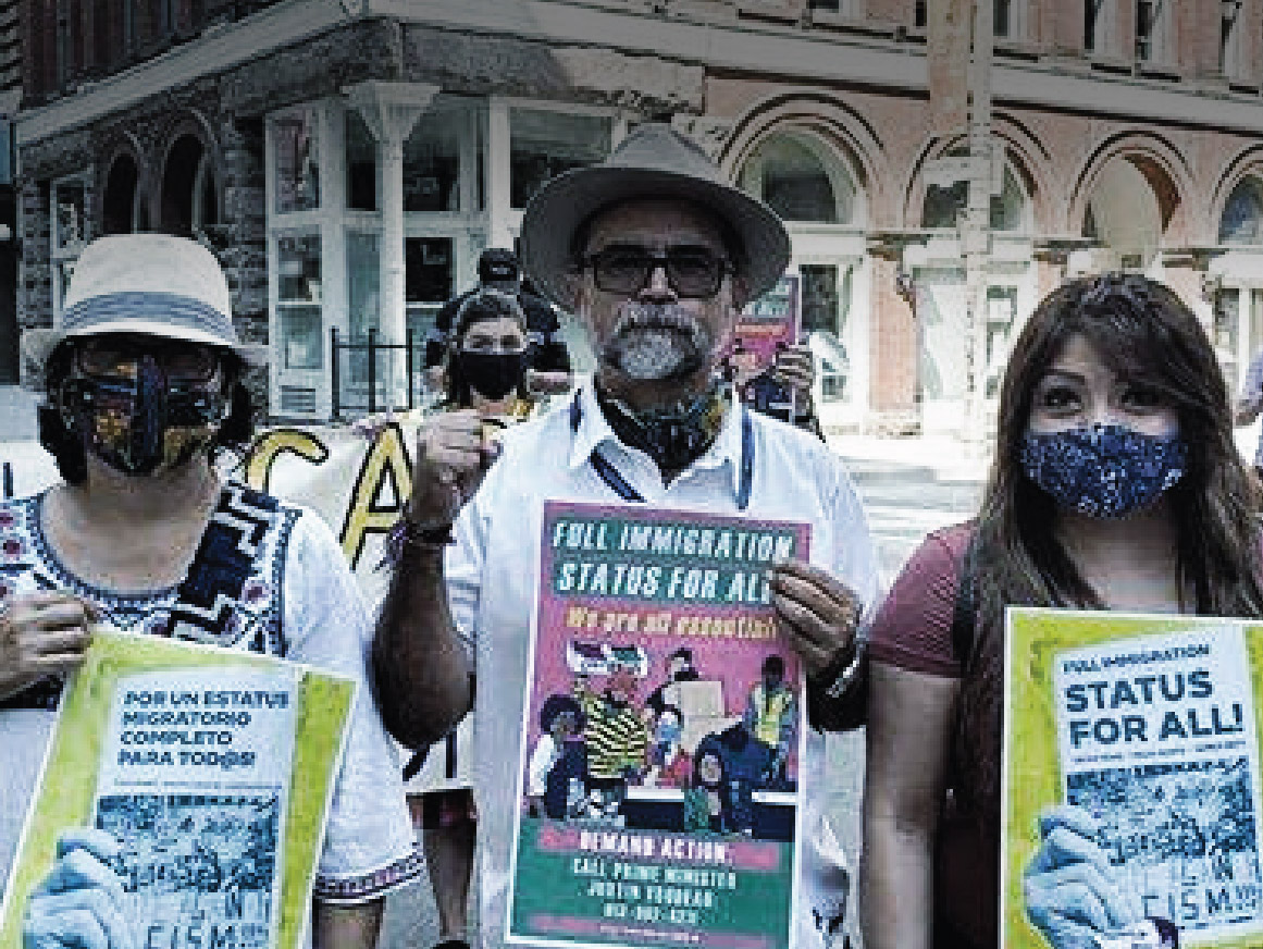 Three people on a city street holding protest signs