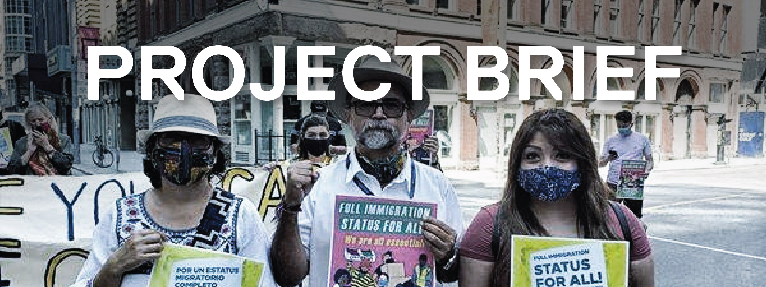 Three people on a city street holding protest signs
