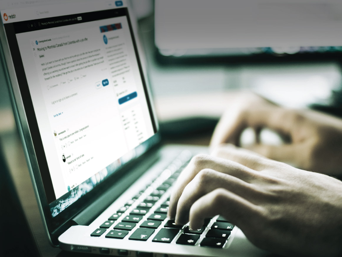 Hands typing on a laptop keyboard with a Reddit thread on the laptop screen