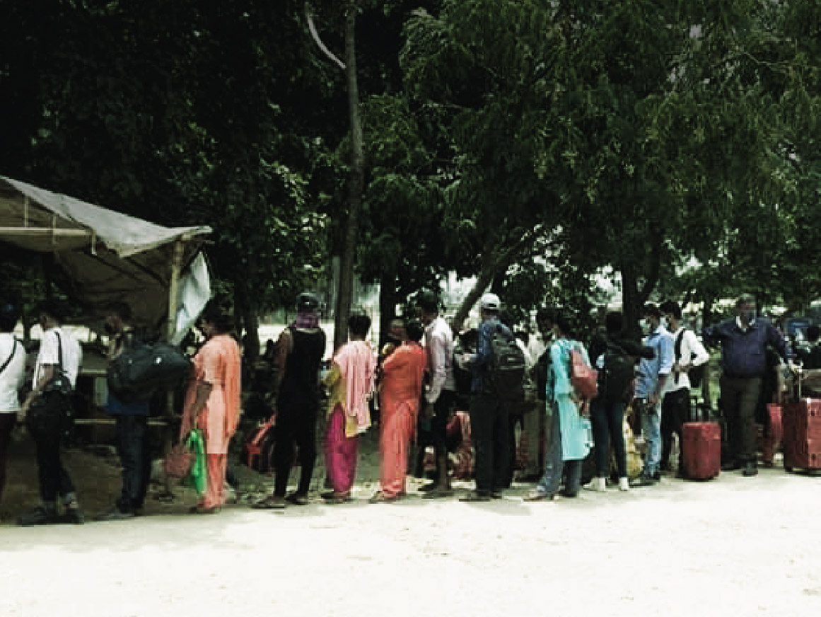 People in a line outside a forested area at Gauriphanta checkpoint in Kailali district returning to work in India 