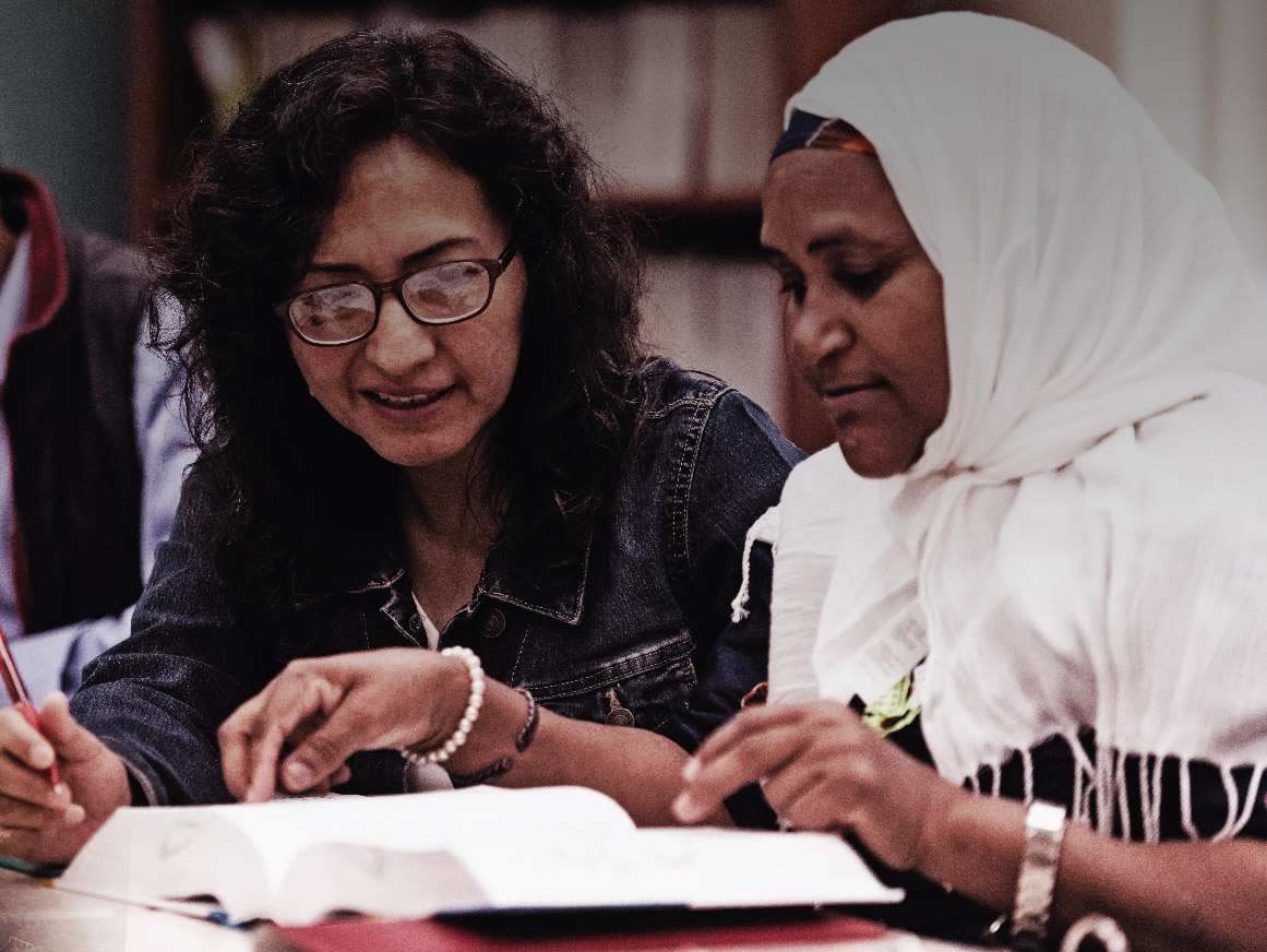 Two women reading together at a desk
