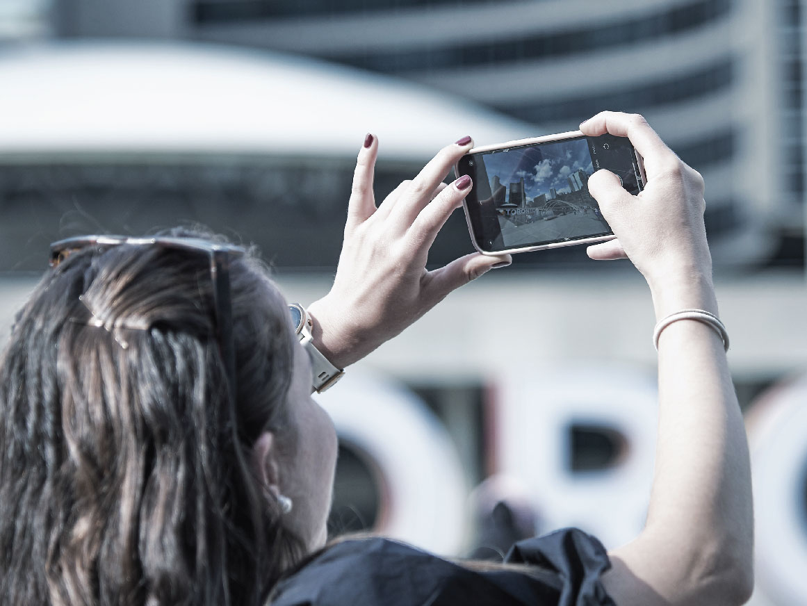 Woman taking a photo on a cell phone in downtown Toronto