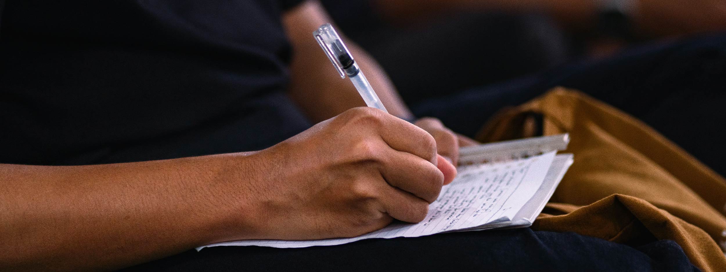 Hand holding a pen writing on a piece of paper