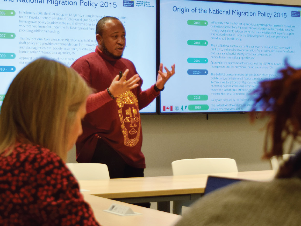 Alexander Oturu presenting in front of a screen