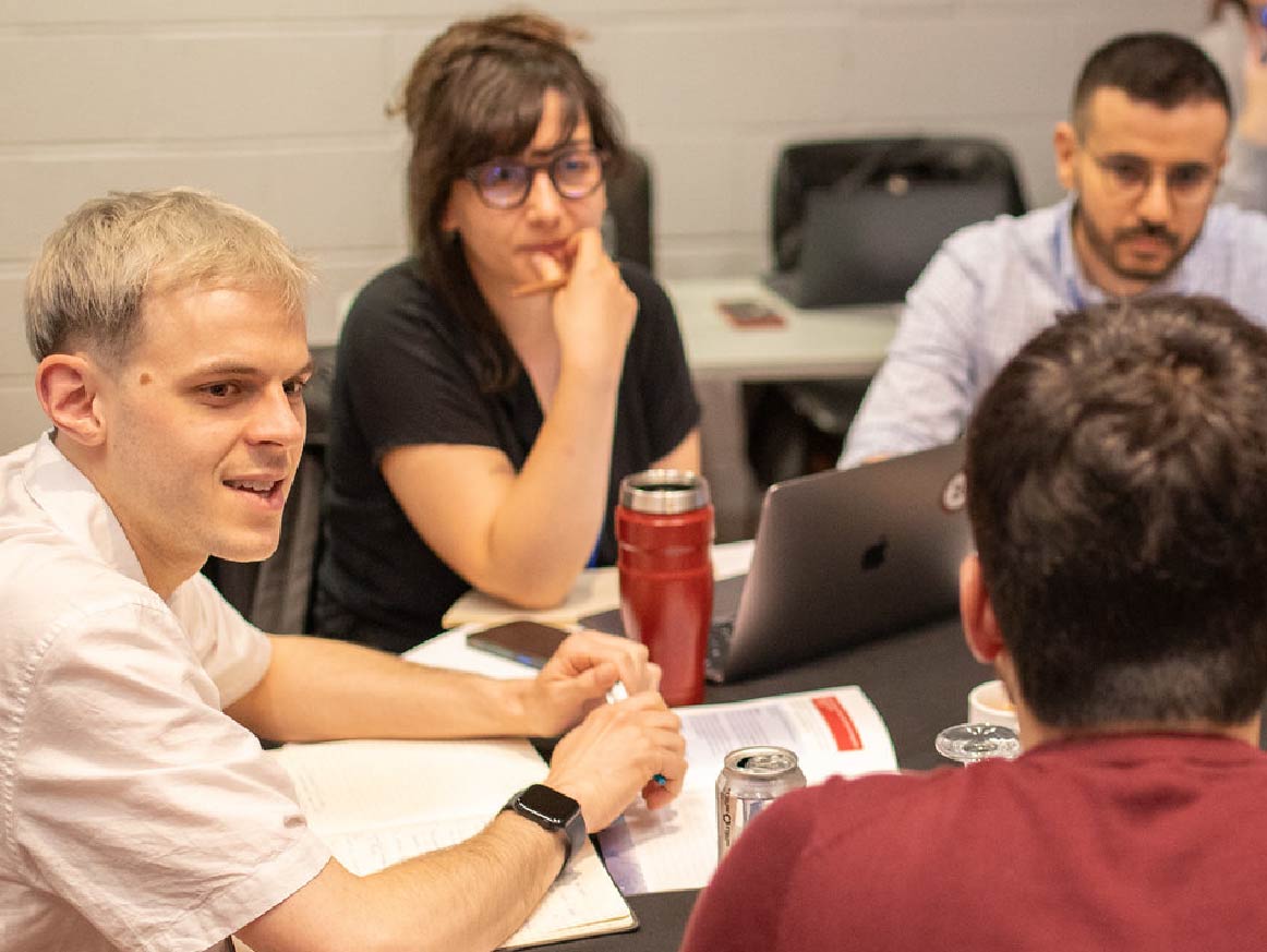 Five researchers sitting at a conference table talking