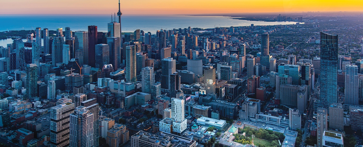 Aerial view of Toronto showcasing its skyline, buildings, and urban layout under a clear blue sky.