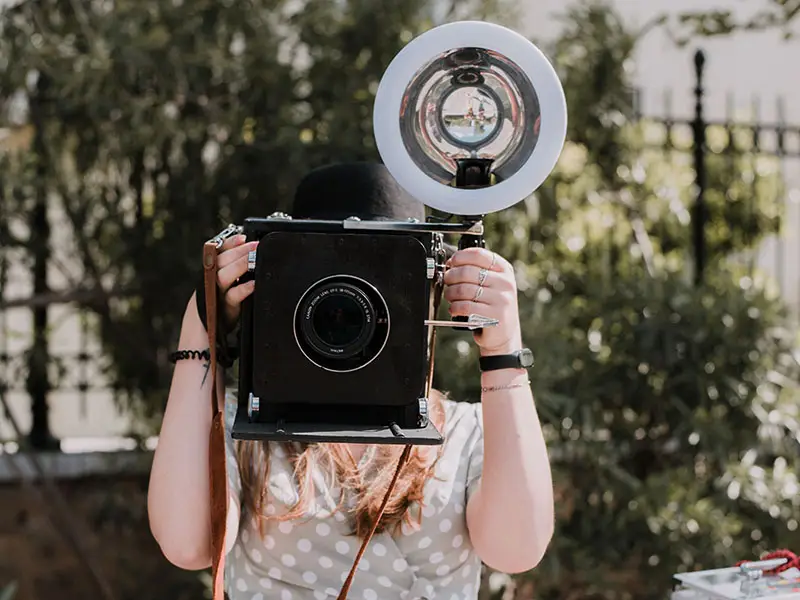 Woman holding large camera with flash