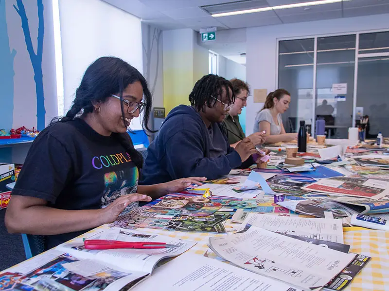 Grad students making vision board collages at a table in DCC