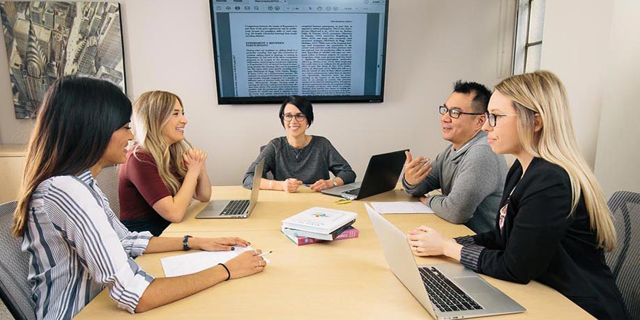 Grad students and professor sitting at table in an office talking