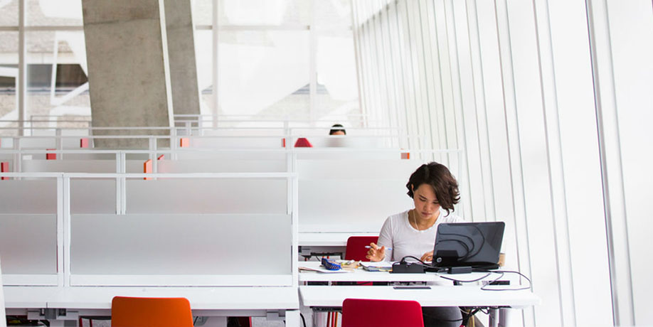 Student studying with laptop in SLC building.