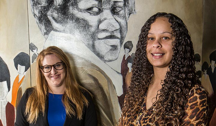 Two MSW students in front of a mural