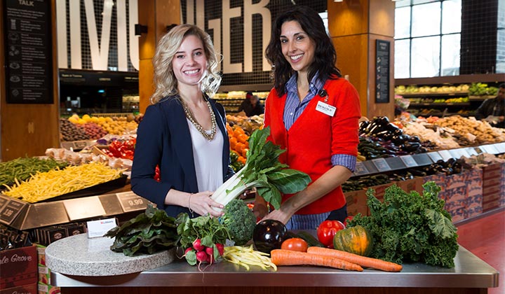 Student and nutritionist stood a table with vegetables in Loblaws, Maple Leaf Gardens