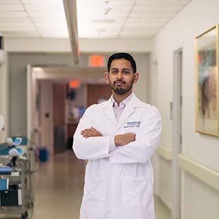 Grad student wearing lab coat in hospital hallway