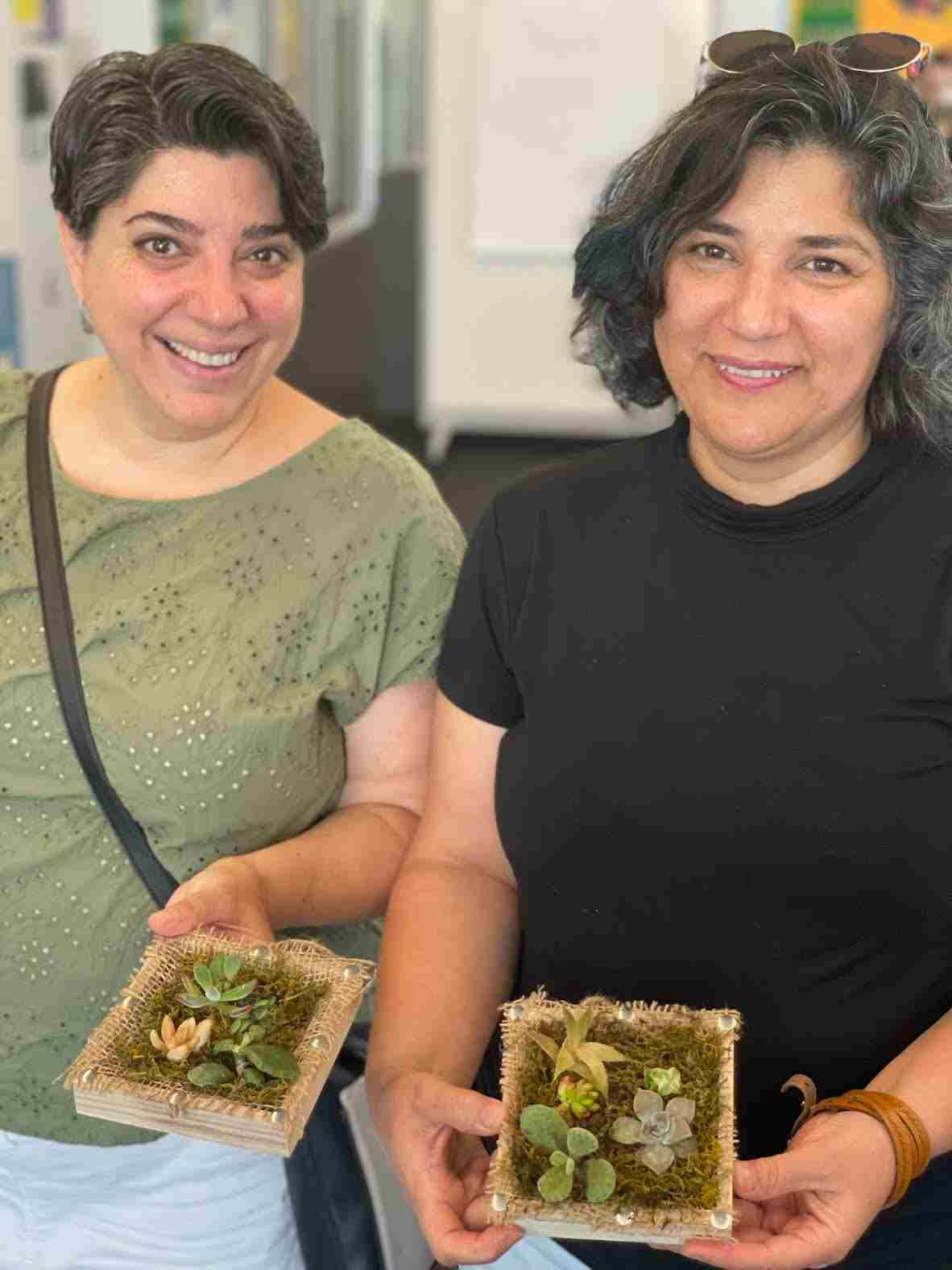 Two female graduate students holding succulent boxes at GRAD Art Break event 