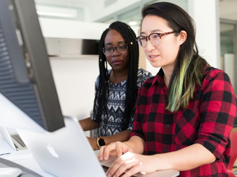 Two female graduate students in computer lab looking at the same computer screen