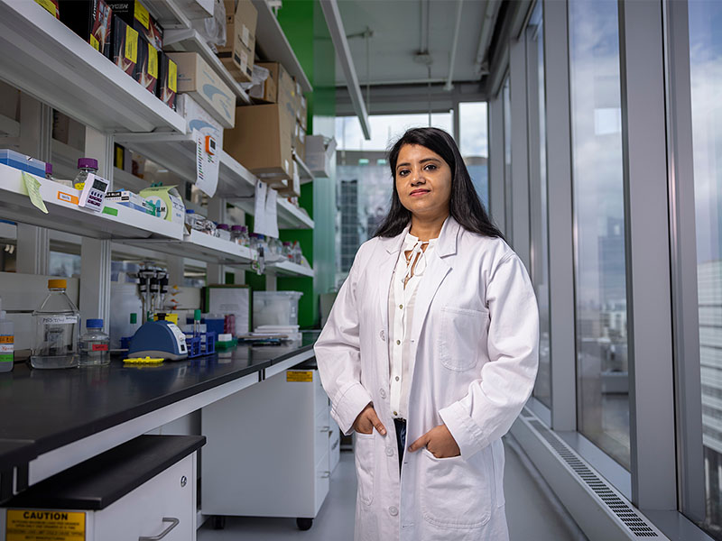Dr. Saujanya Acharya standing with hands in lab coat pockets