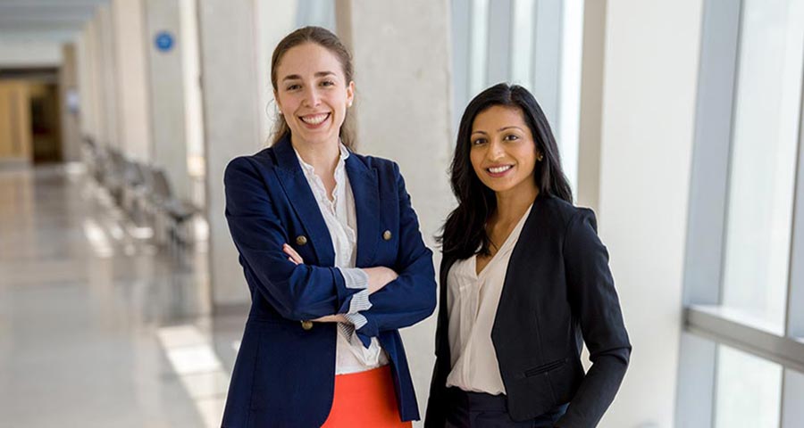 Two business students stand together in a hallway