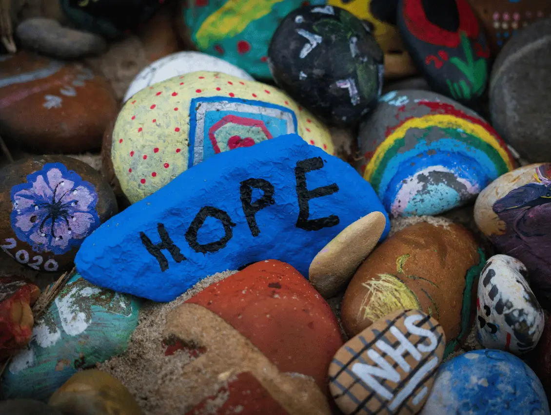 Colourful painted kindness rocks, including a bright blue stone marked “HOPE,” a rainbow, flowers and “2020,” convey an uplifting message