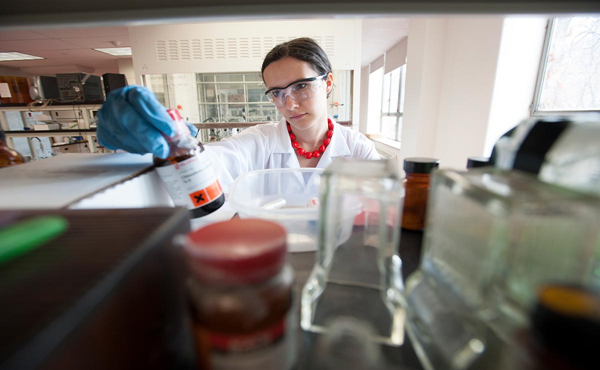 A scientist looks at a bottle in a lab.