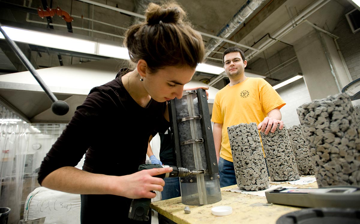 Civil engineering graduate students drill into materials in lab