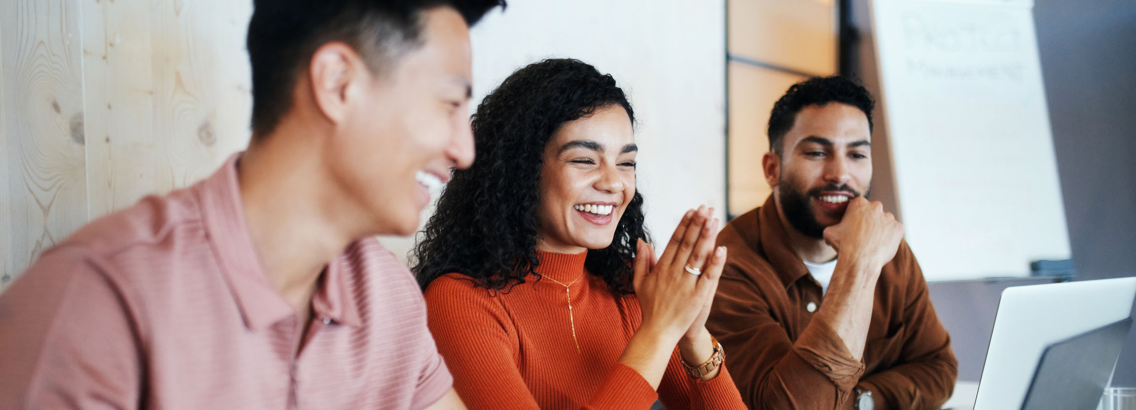 Three smiling graduate students sitting together in front of a laptop