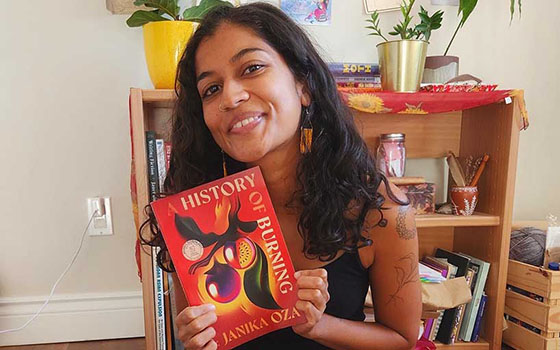 Janika Oza holding her debut novel A History of Burning