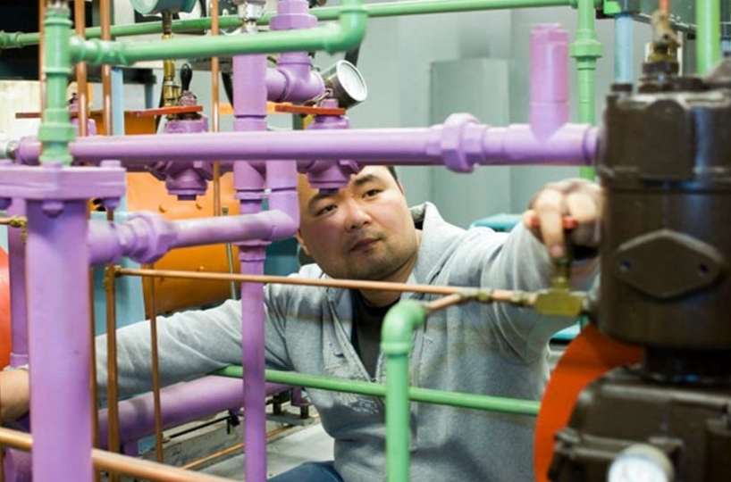 Mechanical and Industrial Engineering student looks through multi-coloured pipes.