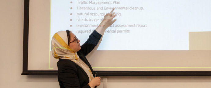 Female grad student wearing hijab pointing at text on projection screen