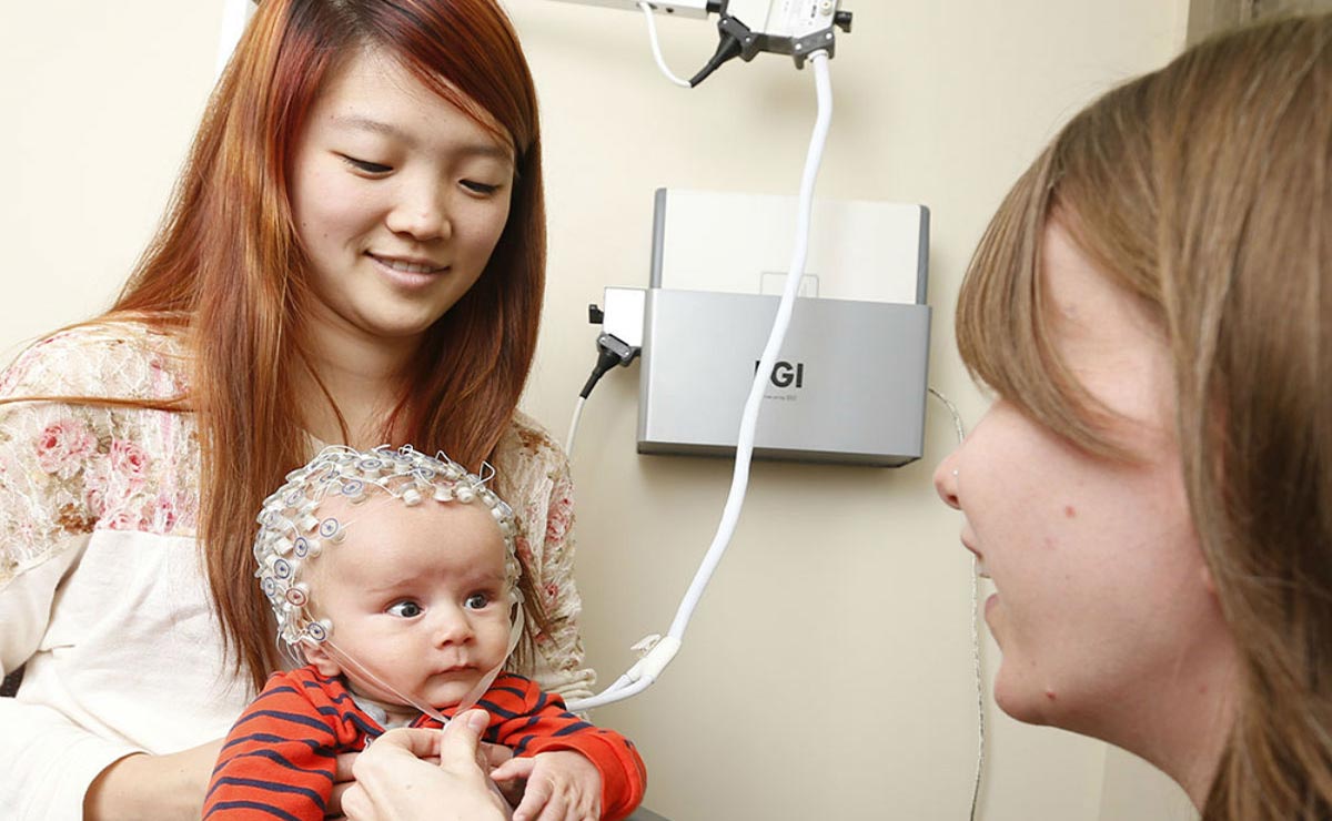 Psychology student with baby on lap who is wearing an eeg tracking headset