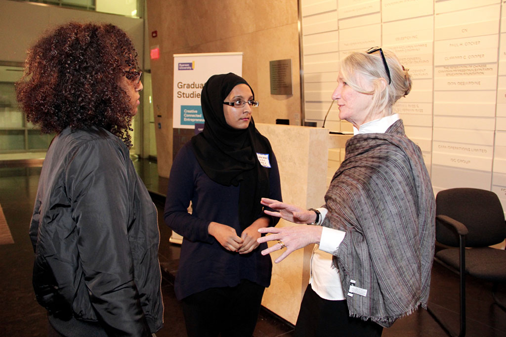 Dr. Barbara Crow speaking with two female graduate students