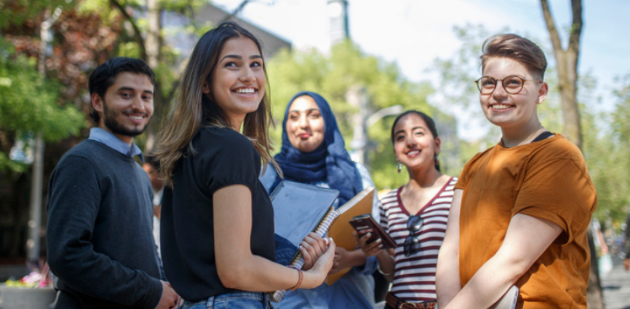 Five students posed and smiling outside on TorontoMet campus