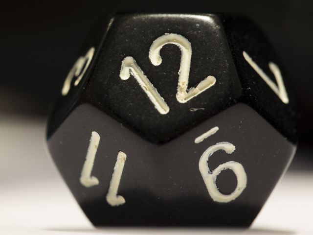 Macro shot of a black twelve-sided die on side showing a twelve