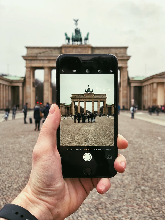 An iphone is held in front of a historic site in Berlin, Germany.