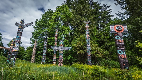 A collection of Totem Poles in from of green trees