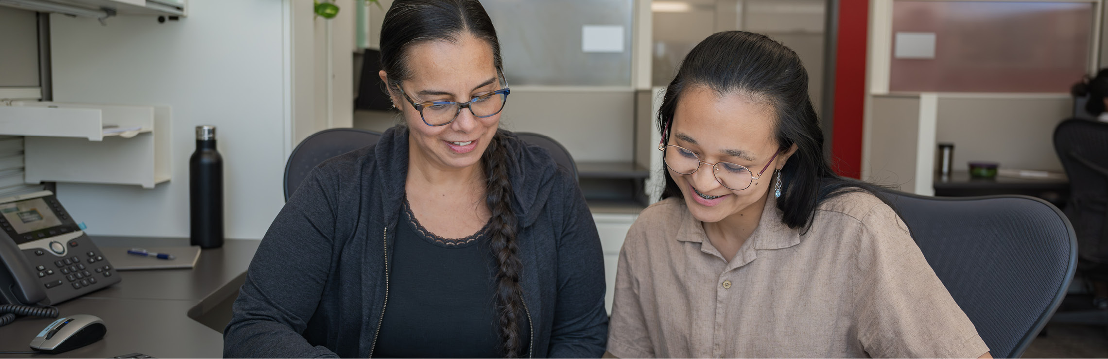 Two employees smiling and collaborating together.